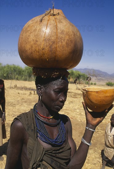 UGANDA, Karamoja, Moroto District, Karamojong woman carrying water gourd on her head.
