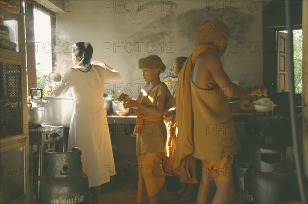 THAILAND, Wat Phra Acha Tong, Novice Buddhist monks from The Golden Horse Forest Monastery in kitchen area receiving food from female cook.