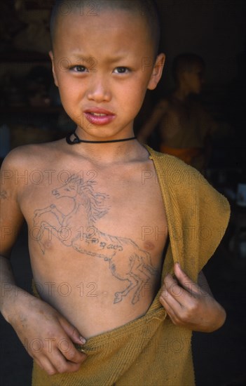 THAILAND, Wat Phra Acha Tong, Portrait of young novice Buddhist monk from The Golden Horse Forest Monastery with rearing horse tattooed across his chest.