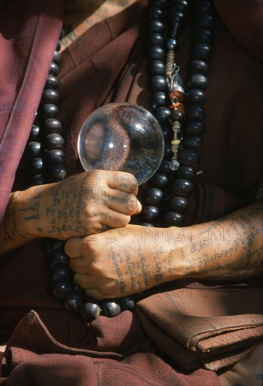 THAILAND, Wat Phra Acha Tong, Cropped vew of Buddhist monk from The Golden Horse Forest Monastery showing tattooed arms and hands and prayer beads.