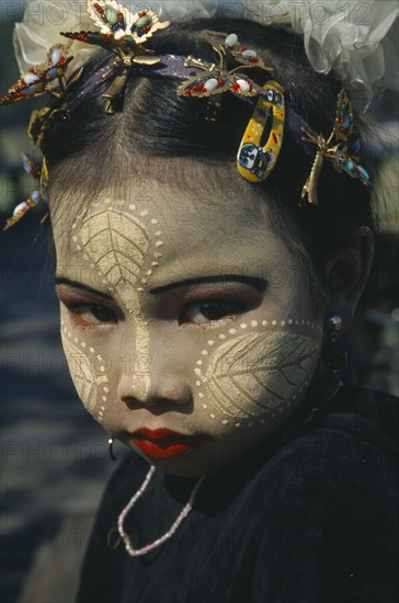 MYANMAR, Lake Taungthaman , Portrait of young girl with face decorated with leaf patterns  and makeup.