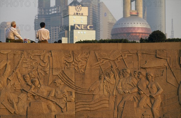 CHINA, Shanghai, The Martyr’s Monument.  Detail of relief carving with two men sitting on top of wall above looking out towards city buildings.