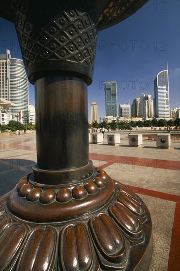 CHINA, Shanghai, People’s Square.  Circular paved area surrounded by skyscrapers with part view of sculpture in the foreground.