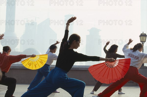 CHINA, Shanghai, Early morning group exercise using fans on the Bund.