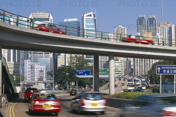 CHINA, Hong Kong, Elevated highway and traffic with city skyscrapers behind.