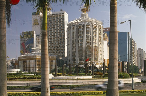 CHINA, Macau, Casino Lisboa.  Exterior framed by palm tree trunks in foreground.