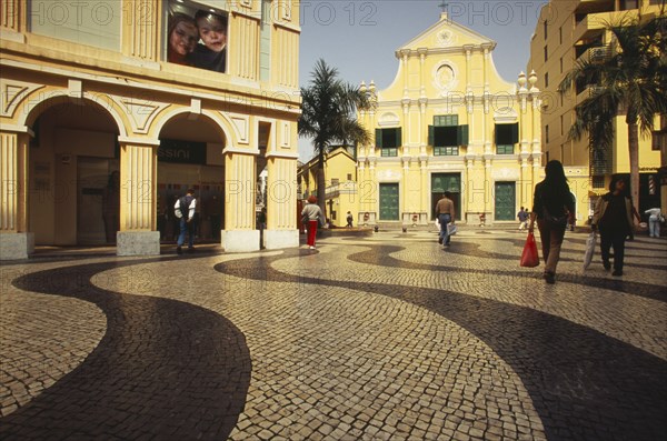 CHINA, Macau, Church of St Dominic.  Exterior with people walking across mosaic tiled area in the foreground.