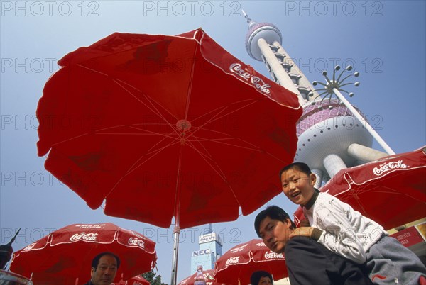 CHINA, Shanghai, Oriental Pearl communications tower built 1991-1995 and designed by Jia Huan Cheng.  People beneath red parasols with Coca Cola logo in foreground.