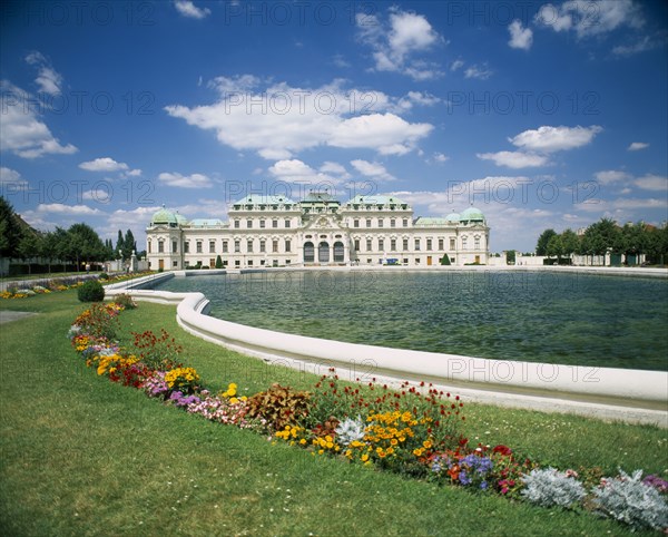 AUSTRIA, Vienna, Belvedere Castle exterior and ornamental lake with colourful flower border in the foreground.
