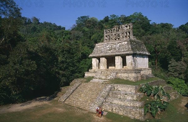 MEXICO, Chiapas, Palenque, Mayan ruins dating from 600 to 900 AD.  Temple of the sun with tourist couple at foot of flight of steps to entrance.