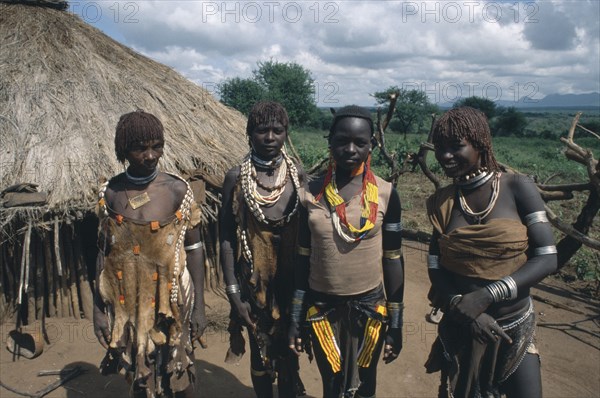 ETHIOPIA, Demeka, Hamer women outside thatched hut.