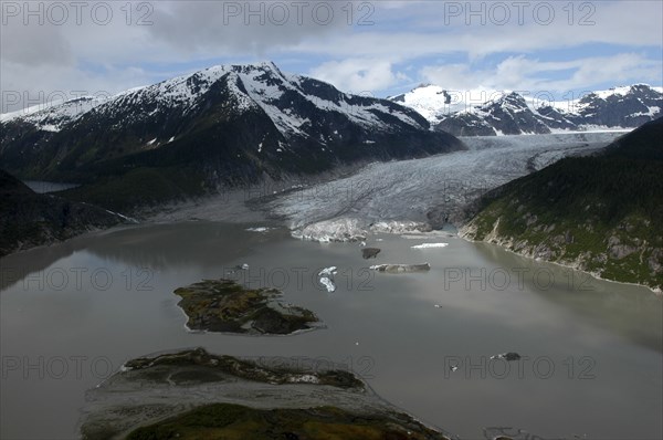 USA, Alaska, Juneau, View over murky waters and valley leading toward snowcapped mountain peaks