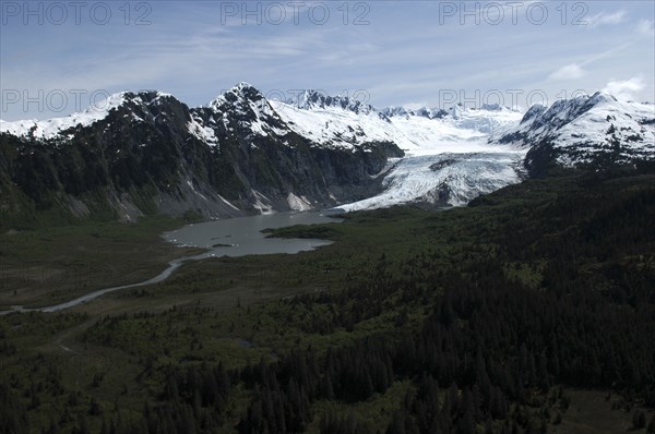 USA, Alaska, Prince William Sound, View over tree covered landscape toward waters and snow capped mountain peaks