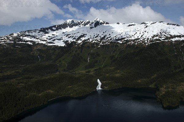 USA, Alaska, Prince William Sound, Aerial view over water and tree covered slopes leading toward snow capped mountain peaks