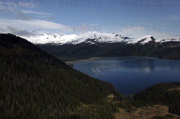 USA, Alaska, Prince William Sound, View over tree covered slopes and waters toward snow capped mountain peaks on the other side