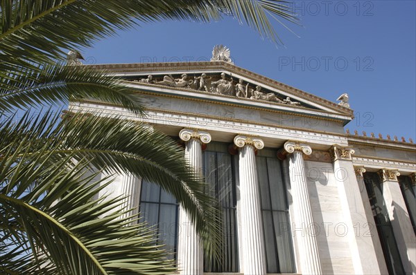 GREECE, Athens, Angled view of the National Academy columned facade partially obscured by palm fronds