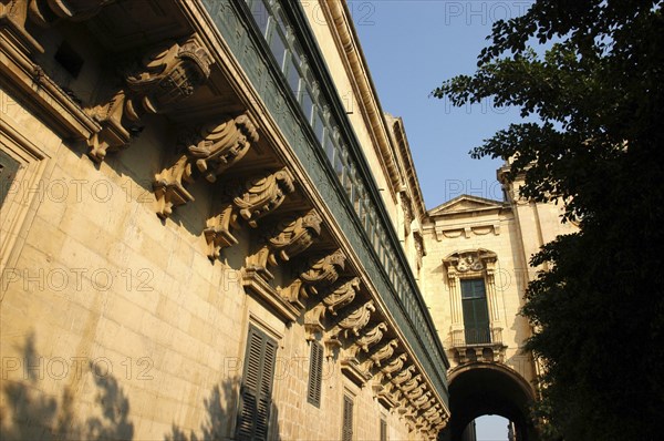 MALTA, Valletta , View along decorative architectural detail of enclosed balcony leading along the side of the building toward an archway