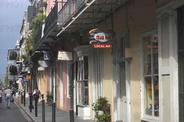USA, Louisiana, New Orleans, French Quarter. View along row of pastel coloured shops with ironwork balconies above