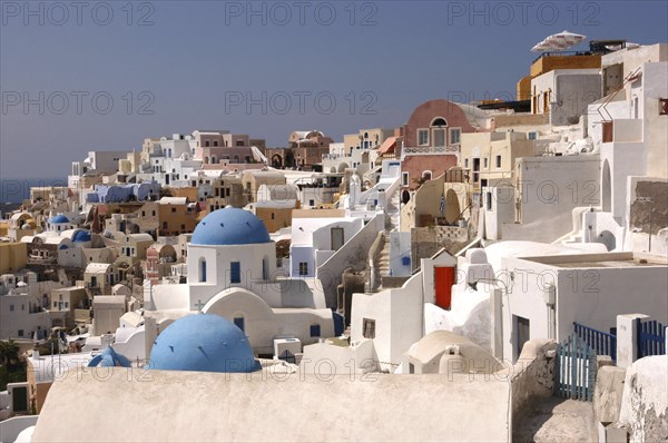GREECE, Cyclades, Santorini, View over the towns predominantly white architecture with blue domed buildings