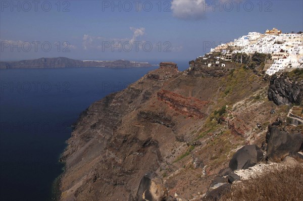GREECE, Cyclades, Santorini, View along rugged coastal cliffs with the white architecture of the town nestled on the clifftop
