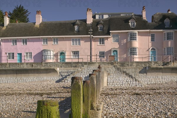 ENGLAND, Dorset, Lyme Regis, View of old fishermens cottages along the waterfront from the beach with a groyne in the foreground.
