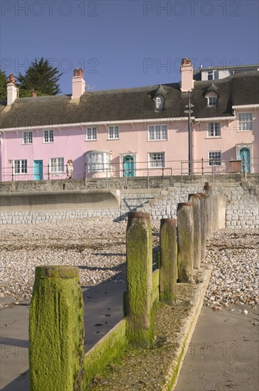 ENGLAND, Dorset, Lyme Regis, View of old fishermens cottages along the waterfront from the beach with a groyne in the foreground.