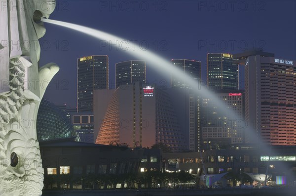 SINGAPORE, Merlion Park, Detail of the Merlion statue at dusk with the Marina Square Complex in the background.