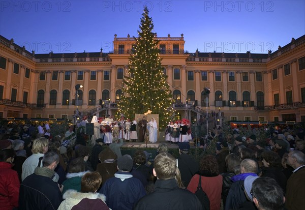 AUSTRIA, Vienna, Crowds watching a nativity scene performed beneath the Christmas tree at the Schloss Schonbrunn Christmas Market.
