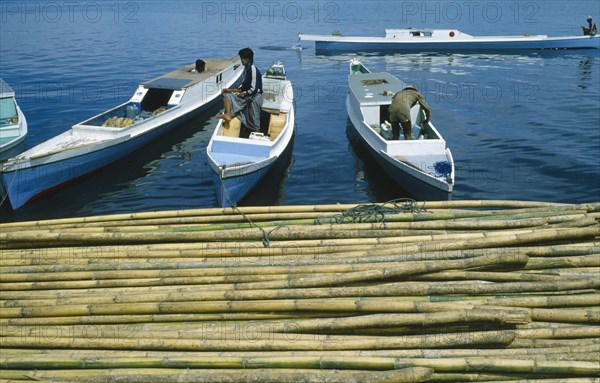 INDONESIA, Industry, Bamboo, Men on boats docking in port with Bamboo at dockside.