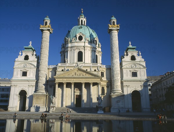 AUSTRIA, Vienna, Karlskirche aka Church of St Charles Borromaeus. View of the facade showing twin columns and domed roof with pool in the foreground