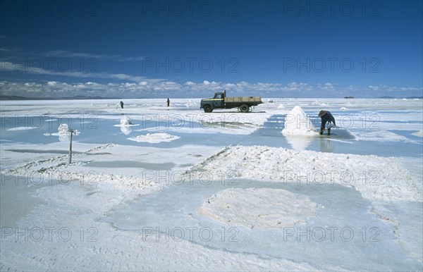BOLIVIA, Altiplano, Potosi, Salar de Uyuni. Salt mounds with workers and collection truck