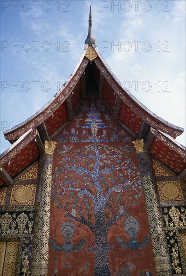 LAOS, Luang Prabang, Wat Xieng Thong.  Ornate temple exterior with Tree of Life mosaic and gold decoration.