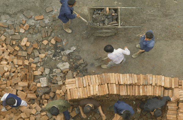CHINA, Sichuan, Chengdu, Construction site.  Looking down on workers stacking bricks and moving rubble.