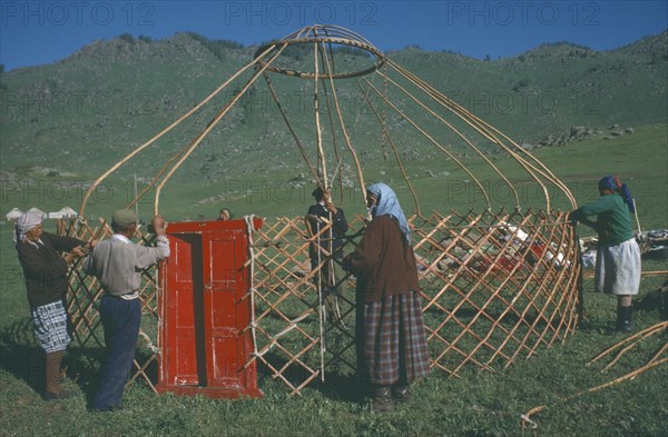 CHINA, Xinjiang, Altai Region, "Kazakh nomads building kigizuy, erecting circular frame and doorway."