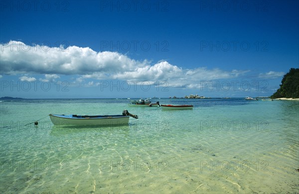 SEYCHELLES, La Digue, "Fishing boats moored in clear, shallow water near beach. "