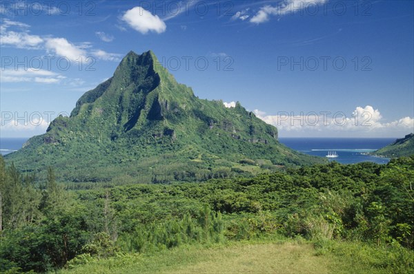 PACIFIC ISLANDS, French Polynesia, Moorea, Landscape with dense vegetation and central jagged peak with sea beyond.