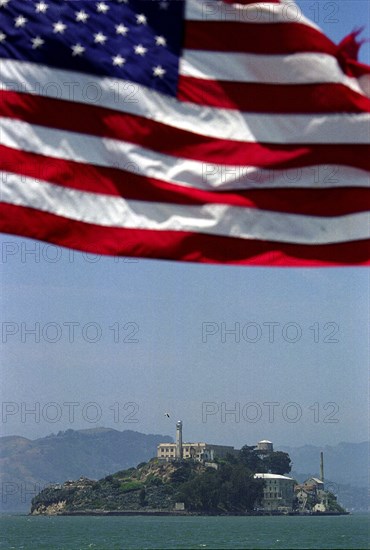 USA, California, San Francisco, Alcatraz Island and Prison in San Francisco Bay with stars and stripes flag flying in the foreground above