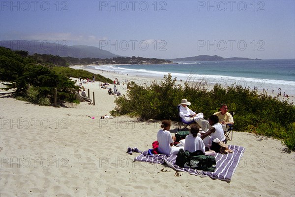 USA, California, Carmel, Carmel Beach with people on blanket among sand dunes in the foreground