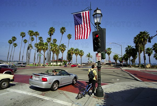 USA, California, Santa Barbara, Traffic lights with flag at the junction of State Street and Cabrillo Blvd. looking out toward Stearns Wharf and West Beach