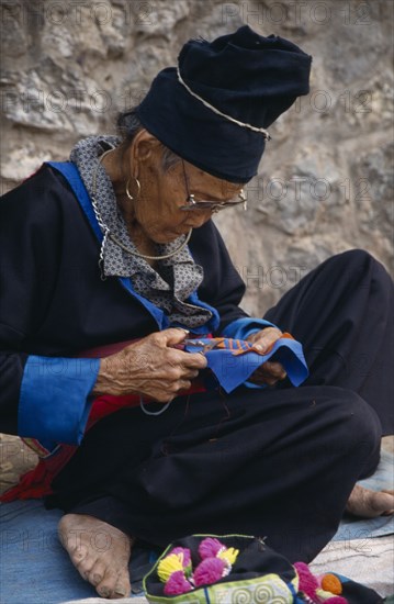 LAOS, Luang Prabang, Hmong woman embroidering traditional textile.