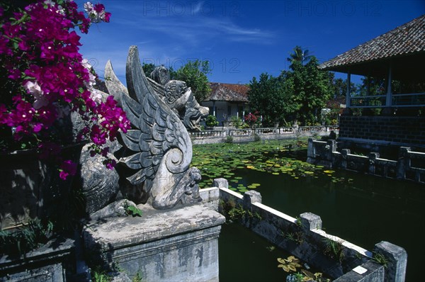 INDONESIA, Bali, Amlapura, Ornamental lake with water lillies at the old palace of the Raja of Karangasem.  Winged dragon statue in foreground.