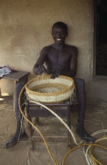 LIBERIA, Upper Lofa, Young man making coil basket.