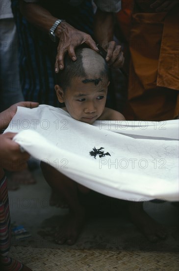 MYANMAR, Yangon, Initiate monk during ritual head shaving.