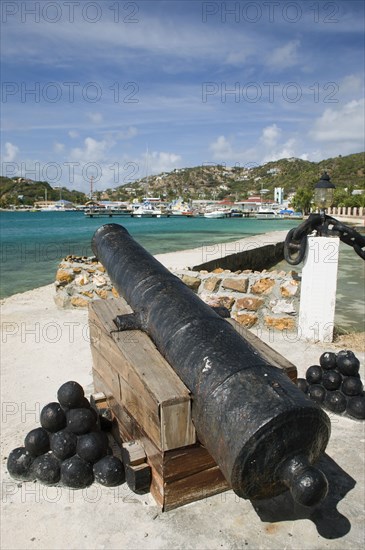 WEST INDIES, St Vincent & The Grenadines, Union Island, Ancient canon on the harbourside at Clifton with the town and mooring behind