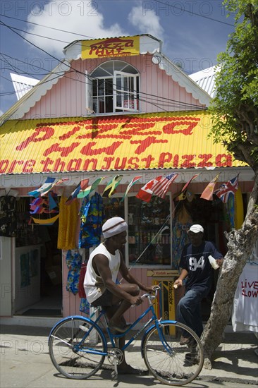 WEST INDIES, St Vincent & The Grenadines, Union Island, Men talking outside pizza restaurant and tourist shop in Clifton