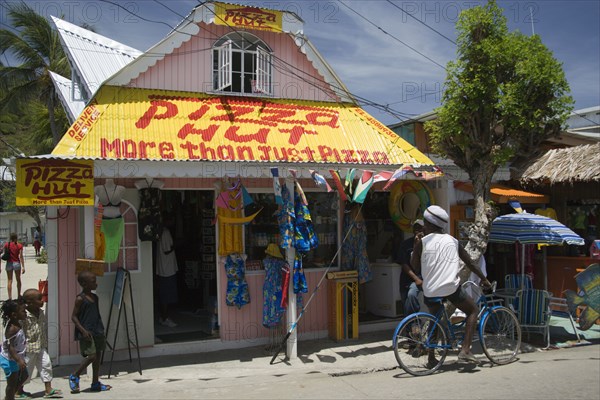 WEST INDIES, St Vincent & The Grenadines, Union Island, Men talking outside pizza restaurant and tourist shop in Clifton