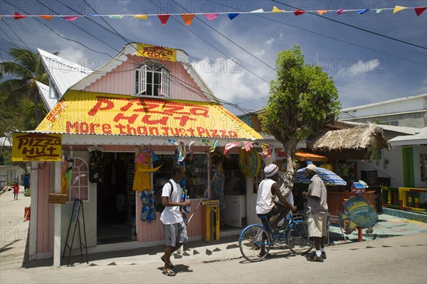 WEST INDIES, St Vincent & The Grenadines, Union Island, Men talking outside pizza restaurant and tourist shop in Clifton