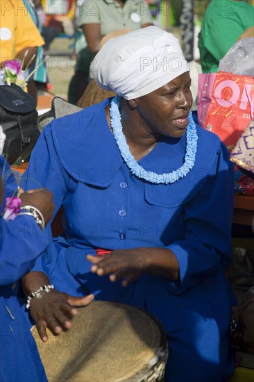 WEST INDIES, St Vincent & The Grenadines, Union Island, Woman playing a drum amongst the Baptist congregation in Clifton at Easter morning harbourside service for those lost at sea