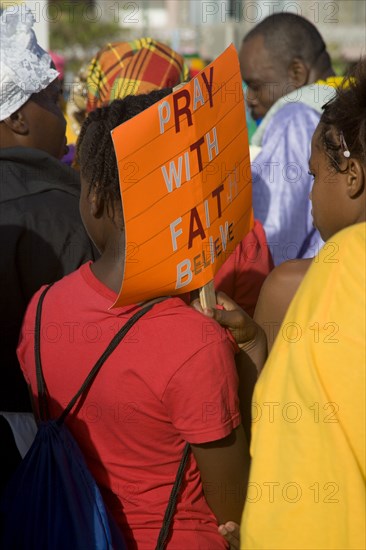 WEST INDIES, St Vincent & The Grenadines, Union Island, Woman carrying a religious placard amongst the Baptist congregation in Clifton at Easter morning harbourside service for those lost at sea