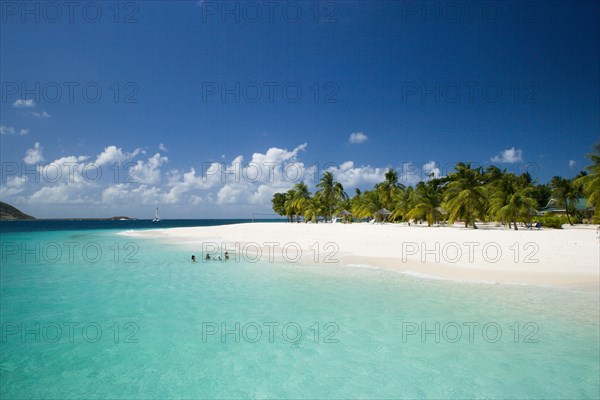 WEST INDIES, St Vincent & The Grenadines, Palm Island, The beach at Palm Island Resort with guests sitting in the water